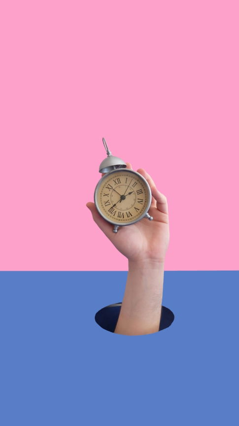 person holding gray and beige roman numeral alarm clock